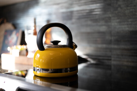 yellow kettle pot on the stove with rock tiles in background and wine glasses 