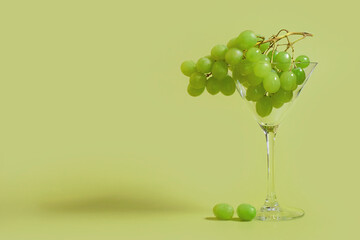 A bunch of green grapes in a martini glass on a colored background