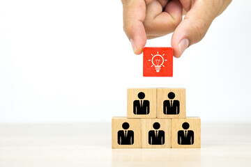 Hand choose cube wooden block stack with lightbulb on human icon stack in pyramid for leadership and business team creative thinking and human resources for teamwork or team player.