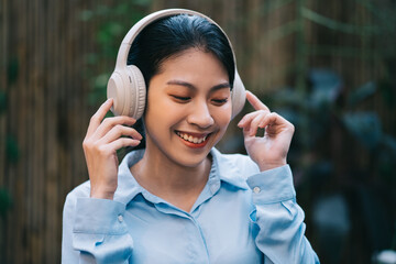 Beautiful young Asian woman listening to music in the garden