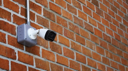 CCTV on on a red brick wall. Modern technology to monitor and prevent mishaps in your shop or office with CCTV with copy space. Selective focus