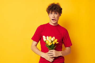 Young curly-haired man in a red t-shirt a bouquet of flowers holiday gift Lifestyle unaltered