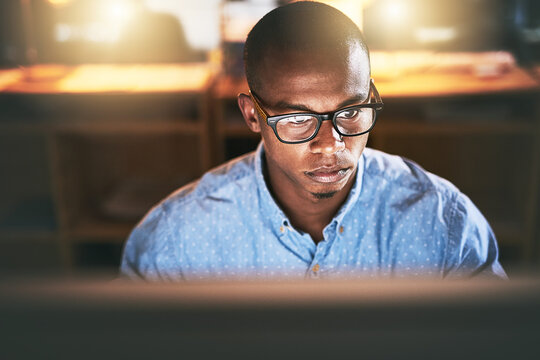 This is what you do when youre passionate about success. Shot of a young businessman using a computer during a late night in a modern office.