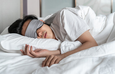 man wearing eye mask is sleeping on the bed 