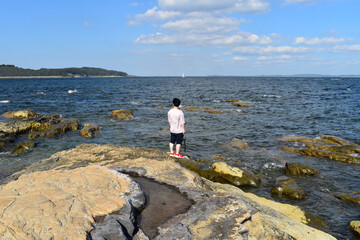 Fototapeta na wymiar パラソルを持って岩の海を散歩するようになった男