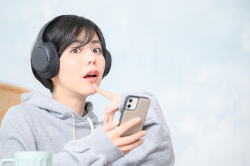 ヘッドフォンをしてスマホを持つ女性