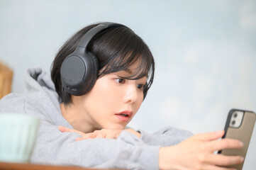 スマホを見ながら音楽を聴く女性