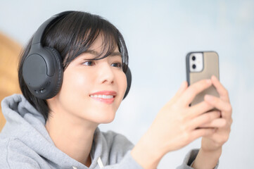 ヘッドフォンで音楽を聴きながらスマホを見る女性　アップ
