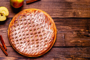 Homemade apple pie with cinnamon on a wooden background.