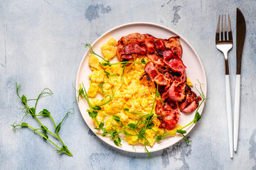 Traditional breakfast scrambled eggs with fried bacon