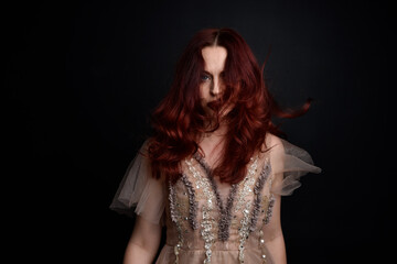 portrait of pretty female model with red hair wearing glamorous fantasy tulle gown and crown. ...