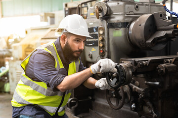 Potrait engineer male in safety hardhat and vest works with heavy machinary in industrail factory