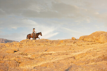 Cowgirl Riding the Skyline on a rocky trail