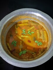 Sambar, mixed vegeterian curry arranged in a white bowl on a black background, Homemade tasty sambar -vegan curry dish, South Indian Kerala special vegetable curry Sambar cooked in clay pot
