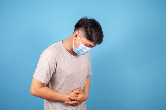 Asian man wear a T-shirt suffering from stomach ache because he has diarrhea on blue background