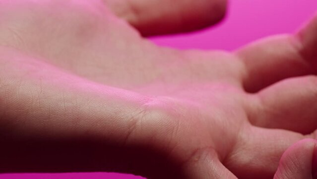 Hand skin in pink neon light, female human body part and ultraviolet, arm surface macro shooting.