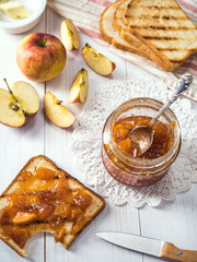 Toasted bread with apple jam on a white wooden background.