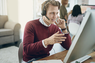 Delivering a high quality customer experience with every call. Shot of a young man using a headset and computer in a modern office.