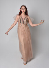  Full length portrait of pretty female model with red hair wearing glamorous fantasy tulle gown and...