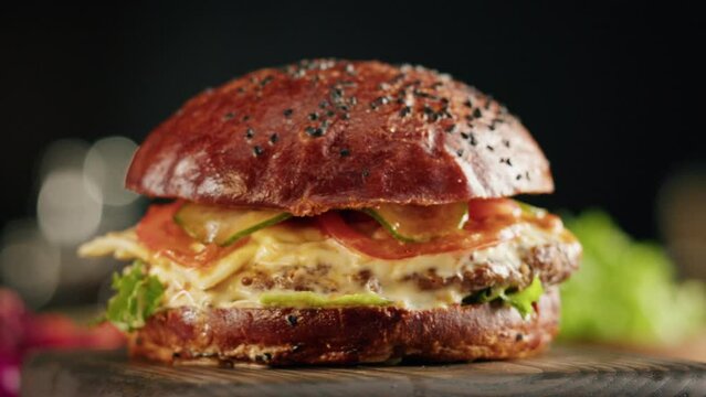 Tasty burger close-up, cooked juicy sandwich, fast food concept, recipe of preparing homemade hamburger with meat and fresh vegetables.
