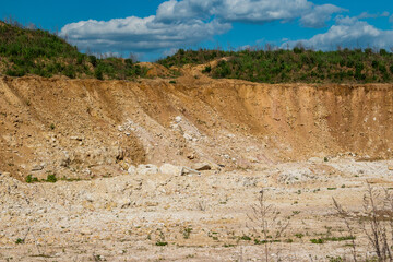 Slope on a limestone quarry, white limestone is covered from above with loamy soil