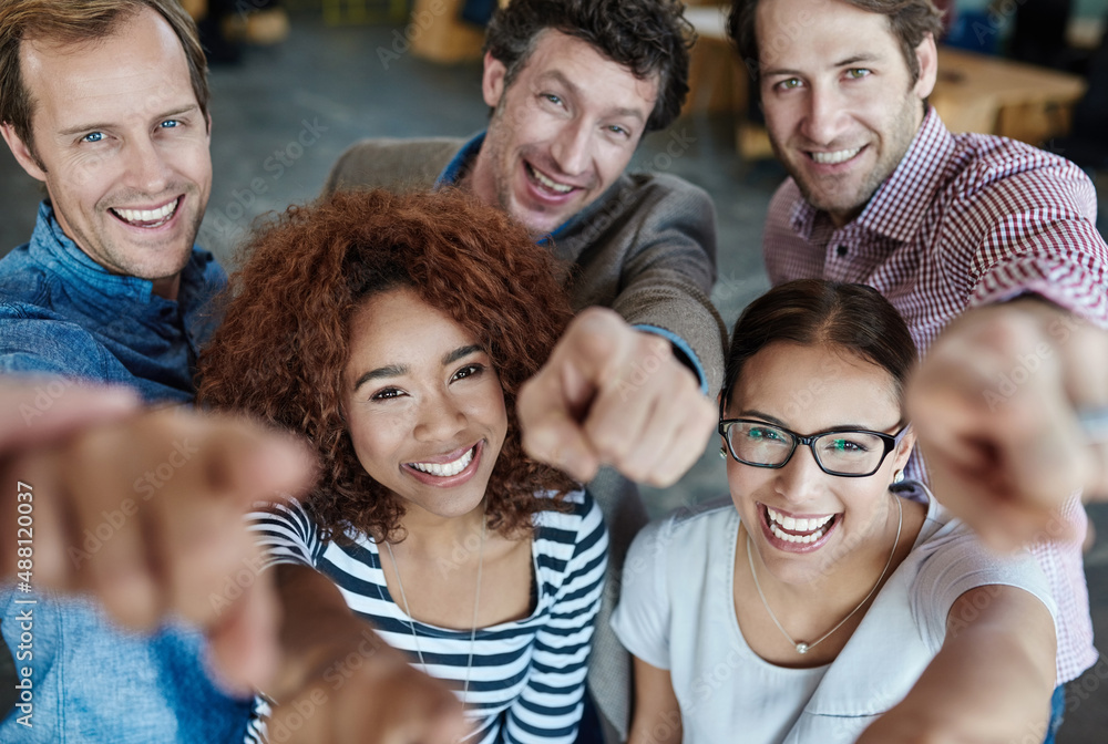 Poster we owe our success to you. portrait of a group of smiling coworkers pointing at the camera while sta