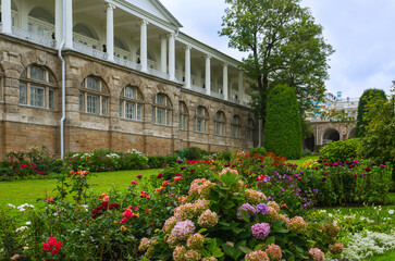 Blooming flower beds in the autumn park against the background of an ancient palace gallery