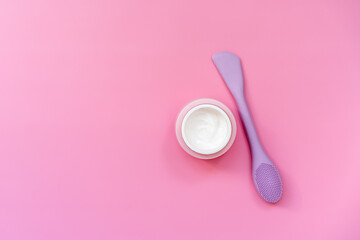 face cream and spatula on pink background, cosmetology, flat lay