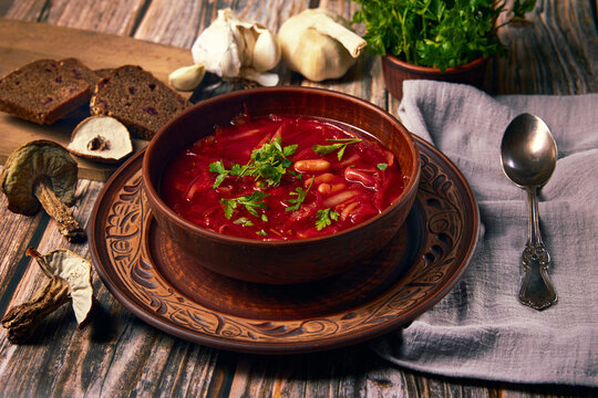 Ukrainian cuisine. Borsch is a Ukrainian soup with porcini mushrooms, cabbage, beetroot, onions, carrots and beans in ceramic plate from ecological red cla