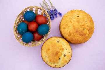 two cakes and painted eggs on a pink background. Top view