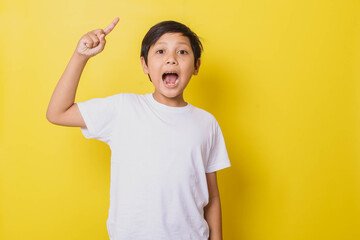 Smart little boy pointing up shouting got an idea isolated on yellow background