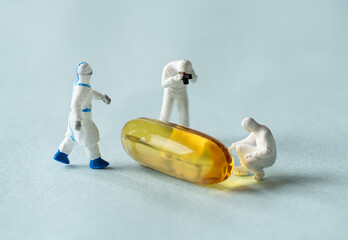 Miniature doctors doing research on pills. Concept for covid-19 medications.