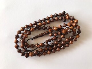 99 Islamic prayer beads on a white background for ramadan, eid adha, eid fitr, flyer islamic and etc . close up of wood tasbih