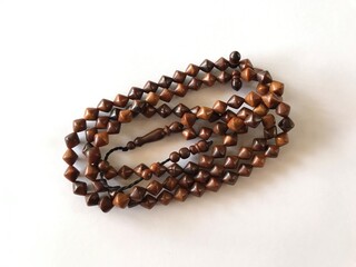 99 Islamic prayer beads on a white background for ramadan, eid adha, eid fitr, flyer islamic and etc . close up of wood tasbih