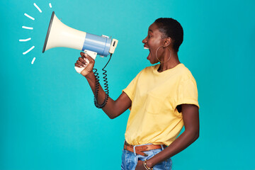 It can take one voice to change the world. Studio shot of a young woman using a megaphone against a...