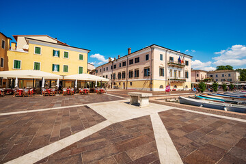 Fototapeta na wymiar Downtown of Bardolino village, promenade in front of the small port with a restaurant and the town hall. Tourist resort on Lake Garda in Verona province, Veneto, Italy, southern Europe.