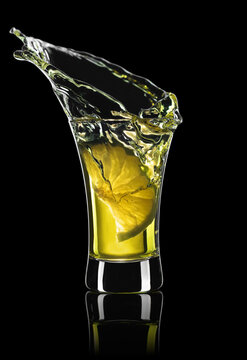 gold tequila shot with lime slice and splash