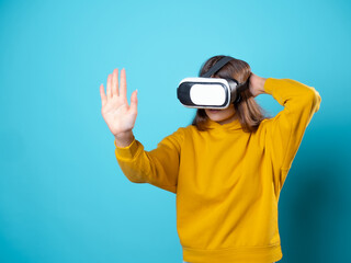 VR gamer, a young woman in a youth outfit uses a virtual reality helmet. Brunette in a yellow...