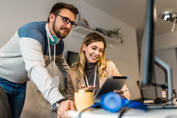 Fototapeta premium Young couple doing business together working at home on the computer and digital tablet.