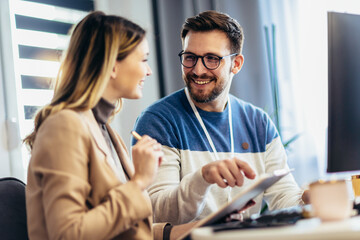Fototapeta premium Successful young couple man and woman working on PC computer together while sitting at table at home
