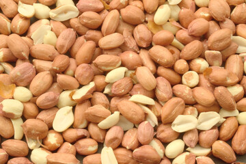 unpeeled, raw peanuts are scattered on the table and make up the background of healthy plant products, the legume family
