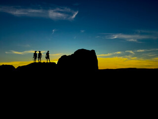 On purpose underexposed view of 3 people -silhouette- standing on a rock during a sunset in Andalusia, Spain