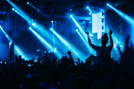 Silhouette of a woman with raised hands on a concert