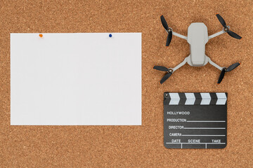 Cork background with a big white paper, a little drone and a clapboard
