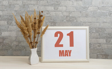 may 21. 21th day of month, calendar date.  White vase with ikebana and photo frame with numbers on...