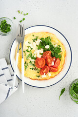 Breakfast fried eggs. Rustic omelette or frittatas with green onions, cheese mozzarella, green arugula and tomatoes on light stone background. Healthy food concept. Copy space. Top view. Mock up.