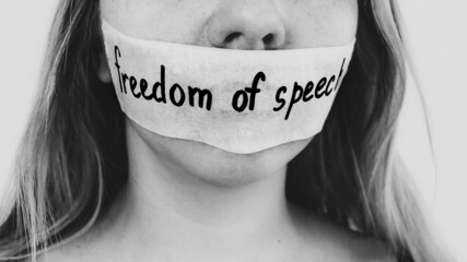 Concept on the theme of freedom of speech: a woman's face is sealed with tape with the inscription Freedom of speech. Concept on the theme of freedom of speech: a woman's face is sealed with tape with