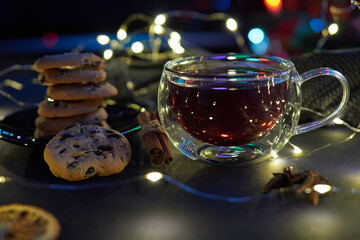 Transparent cup with black tea on blurred holiday lights background