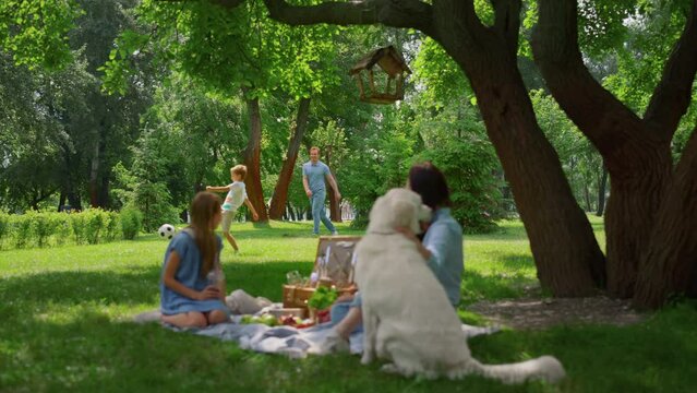Active family leisure on picnic in park. Parents have fun with children and dog.