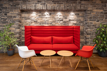 red modern couch chairs and tables illuminated with spotlights in front of retro natural stone masonry